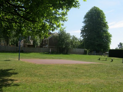 a park with a bench, some trees and a basketball hoop