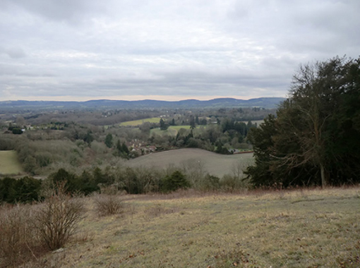 field in the foreground with hills and villages in the background